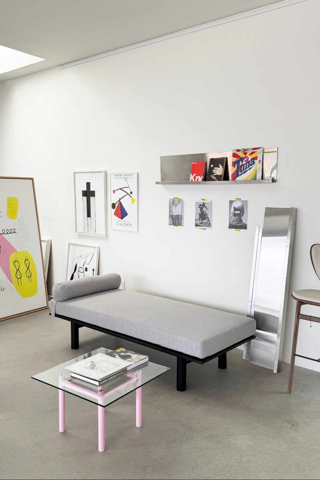 Modern living room with a gray sofa bed, glass coffee table, and wall art.