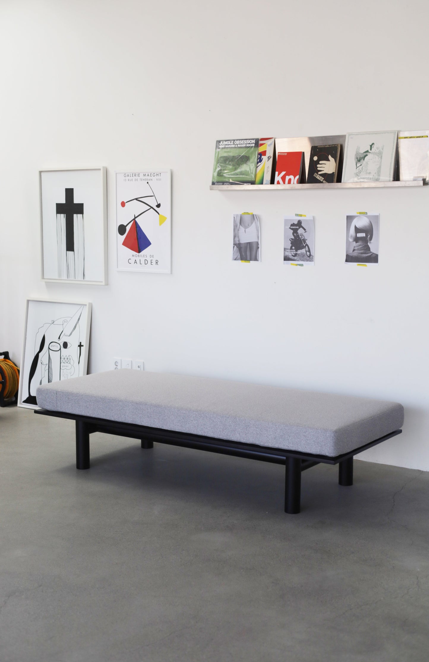 Modern bedroom with a minimalist bed, concrete floor, and wall art.